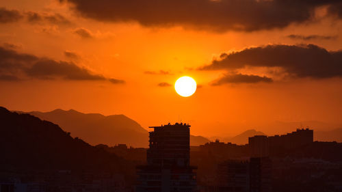 Silhouette buildings against romantic sky at sunset