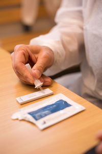 Close-up of man holding paper on table