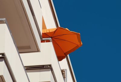 Low angle view of umbrellas against clear blue sky