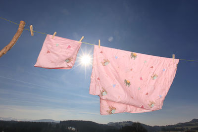 Close-up of clothespins holding laundry on clothesline during sunny day