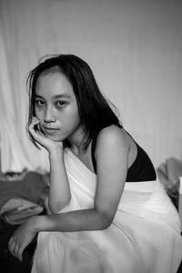 Portrait of young woman sitting on bed at home