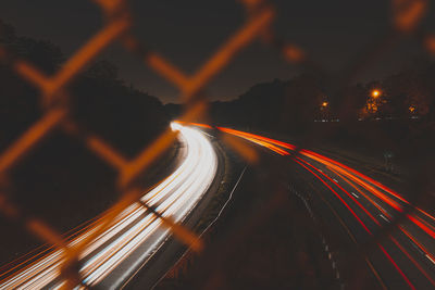 Light trails on road against sky at night