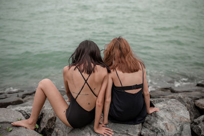 Rear view of woman sitting at sea shore