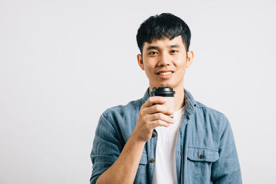 Portrait of young man using mobile phone against white background