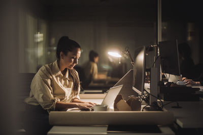 Businesswoman concentrating while working late on laptop in office
