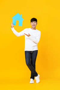 Portrait of young man standing against yellow background