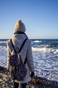 Rear view of woman looking at sea against clear sky