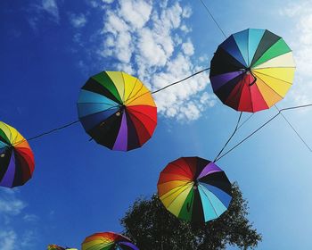 Low angle view of colorful umbrellas hanging on cable against blue sky
