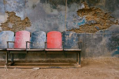 Old abandoned chairs against damaged wall