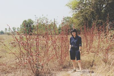 Full length portrait of young woman standing on land