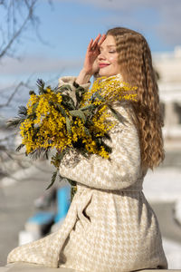 A woman with a bouquet of acacia flowers. the concept of the spring - march 8, easter, women's day.