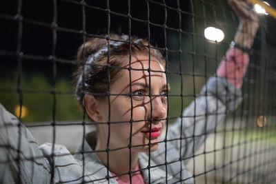 Beautiful woman looking through fence at night