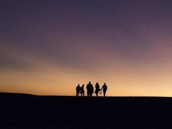 Silhouette people standing on landscape at sunset