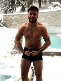 Portrait of shirtless man standing in swimming pool