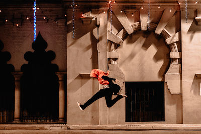 A girl in hijab jumping along the city street at night