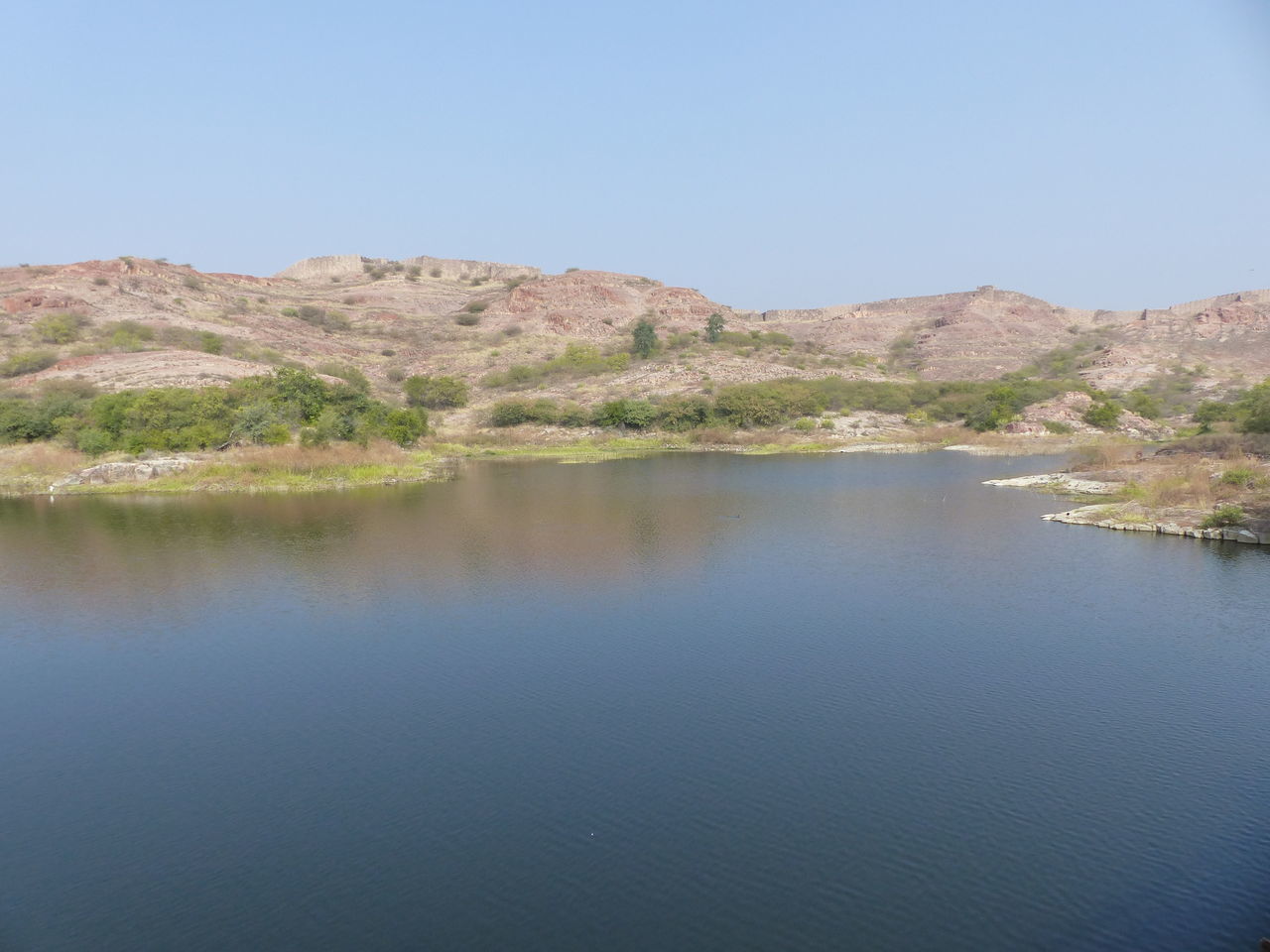 water, scenics - nature, reservoir, landscape, beauty in nature, sky, environment, lake, nature, clear sky, tranquility, reflection, mountain, no people, tranquil scene, land, travel destinations, blue, non-urban scene, day, body of water, copy space, desert, plant, travel, outdoors, sunny, mountain range, tourism, tree, idyllic, remote