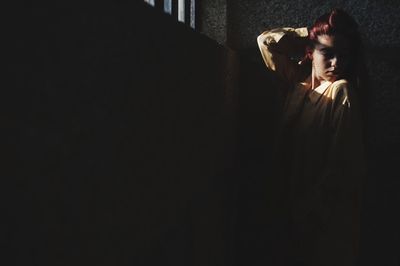 Woman with hand in hair standing against wall