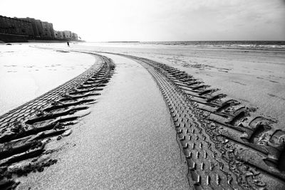 Tire tracks on beach against sky