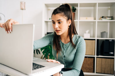 Young woman using phone while sitting on table