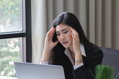 Businesswoman using laptop while working in office