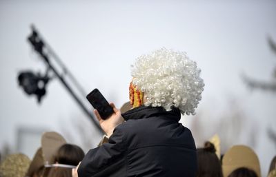 Rear view of man using mobile phone against sky