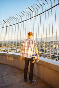 Rear view of man standing on bridge against sky