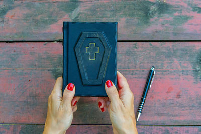 Cropped hands of woman holding bible on table