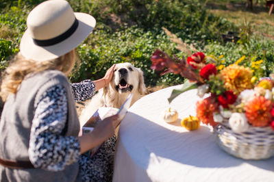 Cute girl in a hat reading a book and petting a labrador dog