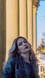 Portrait of beautiful woman standing against columns