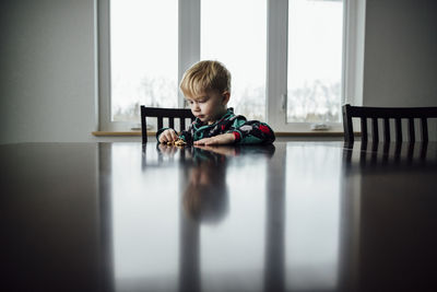Boy playing with toy on table while sitting at home