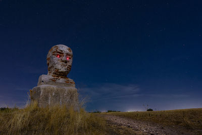 Low angle view of sculpture on field against sky at night