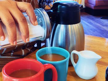 Close-up of hand holding coffee cup on table