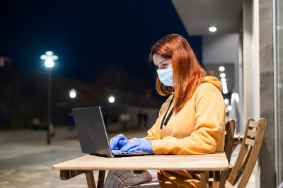 Businesswoman wearing mask using laptop at cafe