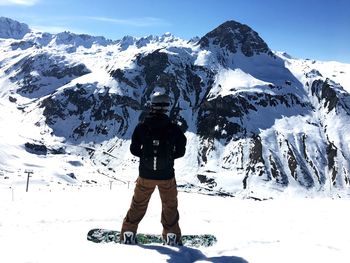 Rear view of person walking on snow covered mountain