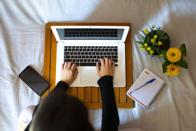 Overhead view of a woman working in bed with the computer.