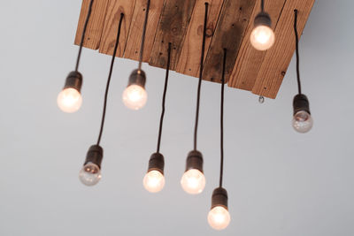 Low angle view of illuminated light bulb hanging on ceiling