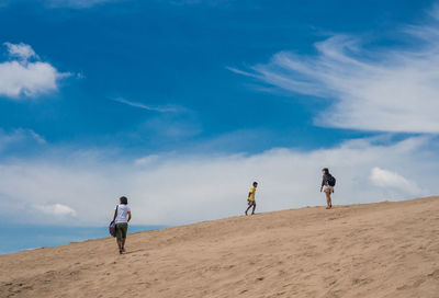 People walking at beach against sky