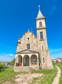 Small ancient church on background of blue sky in countryside. stone stairs, arched windows