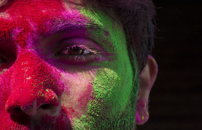 Close-up portrait of young man with powder paint against black background