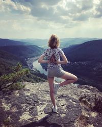 Rear view of woman standing on mountain against sky