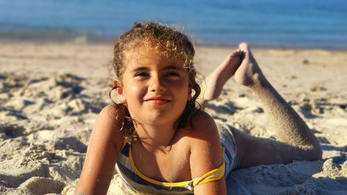 Little girl enjoying in the sand a day at the beach in summer