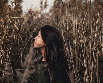 Side view of young woman standing amidst plants