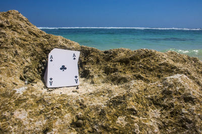 Information sign on rock by sea against sky