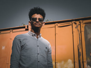 Portrait of young man wearing sunglasses while standing against sky