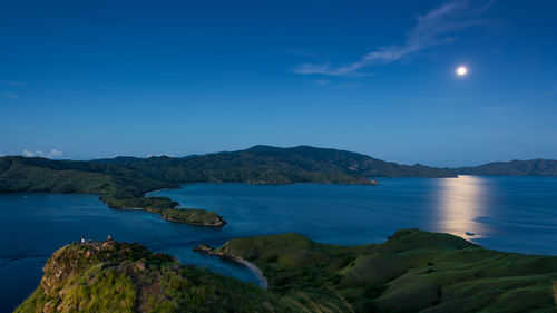 Scenic view of sea and mountains against blue sky