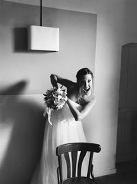 Portrait of woman sitting on wall at home