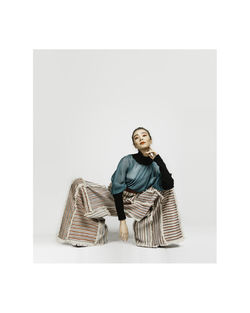 Portrait of smiling young woman sitting against white wall