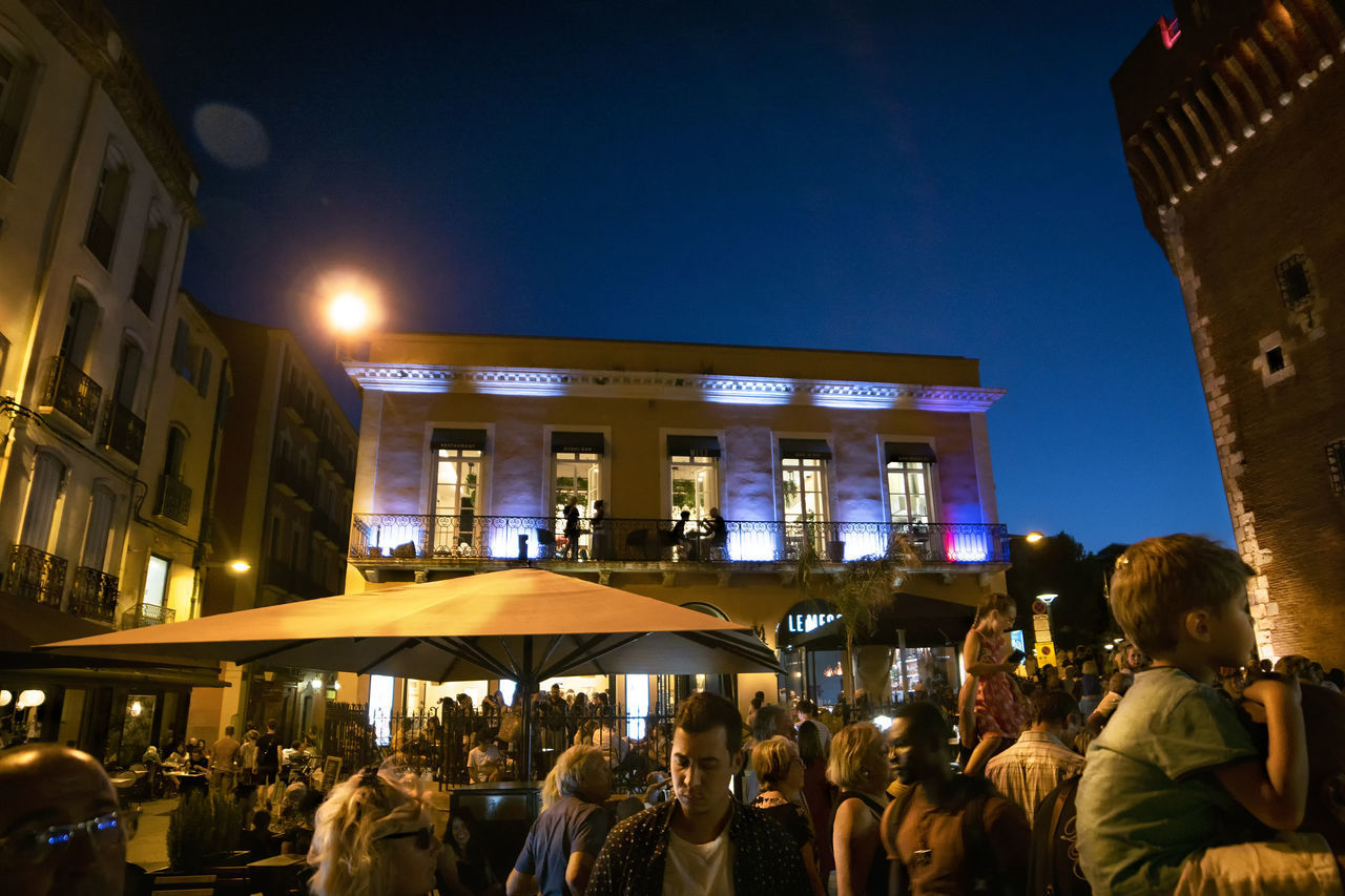 GROUP OF PEOPLE IN ILLUMINATED BUILDING AT NIGHT