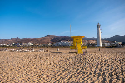 Tranquil morning on the beach with a 
 lighthouse 