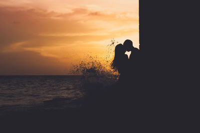 Silhouette of couple kising against sky at sunset